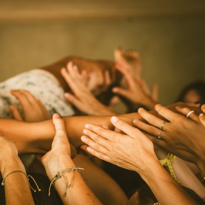 Viele Frauenhände, die sich im Kreis gegenseitig berühren und halten