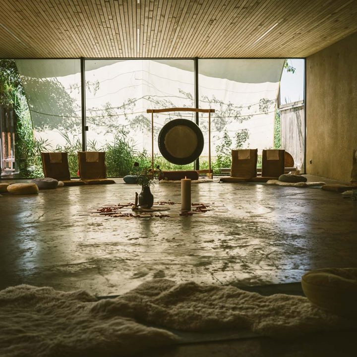 Lichtdurchfluteter Retreat-Raum mit Gong, Kerze und Sitzkissen im Kreis
